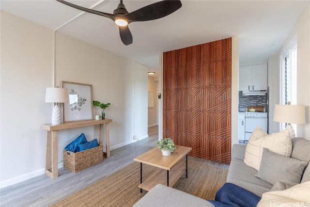 living room with a ceiling fan, baseboards, and wood finished floors