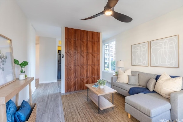 living room with wood finished floors, a ceiling fan, and baseboards