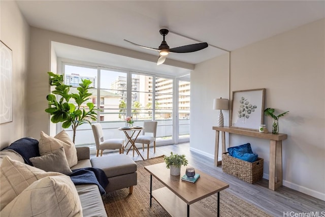 living room with wood finished floors, a ceiling fan, and baseboards