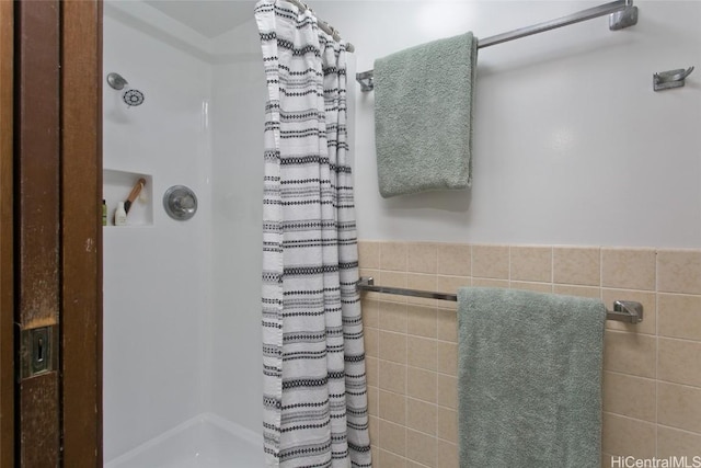 full bathroom with a wainscoted wall, curtained shower, and tile walls