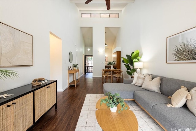 living room with ceiling fan, baseboards, a high ceiling, and wood finished floors