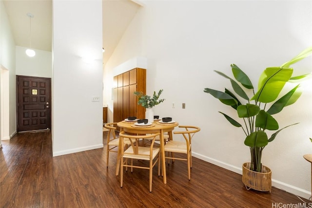 dining area with dark wood finished floors, baseboards, and a towering ceiling