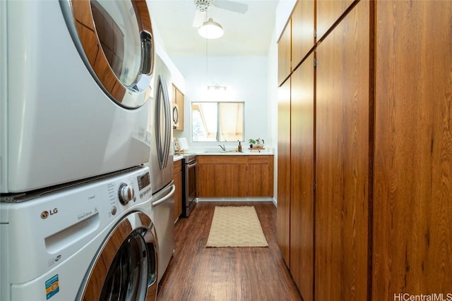 laundry room with a sink, stacked washer / drying machine, dark wood-style floors, and laundry area