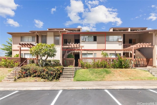 view of property featuring stairway and uncovered parking