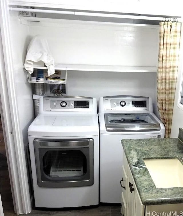 clothes washing area featuring washing machine and dryer, cabinet space, and a sink