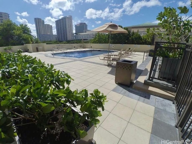 community pool featuring a view of city, a patio area, and fence