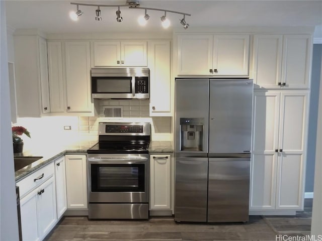 kitchen featuring white cabinets, stone countertops, tasteful backsplash, and stainless steel appliances