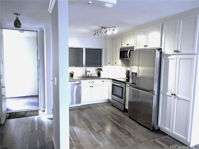 kitchen featuring stainless steel appliances, dark wood-type flooring, a sink, white cabinetry, and ornamental molding