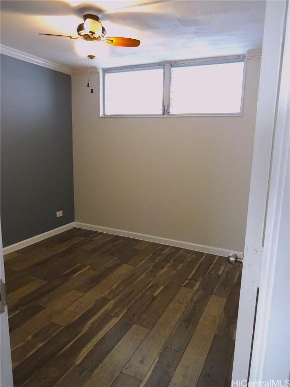 unfurnished room featuring ornamental molding, dark wood-type flooring, baseboards, and a ceiling fan