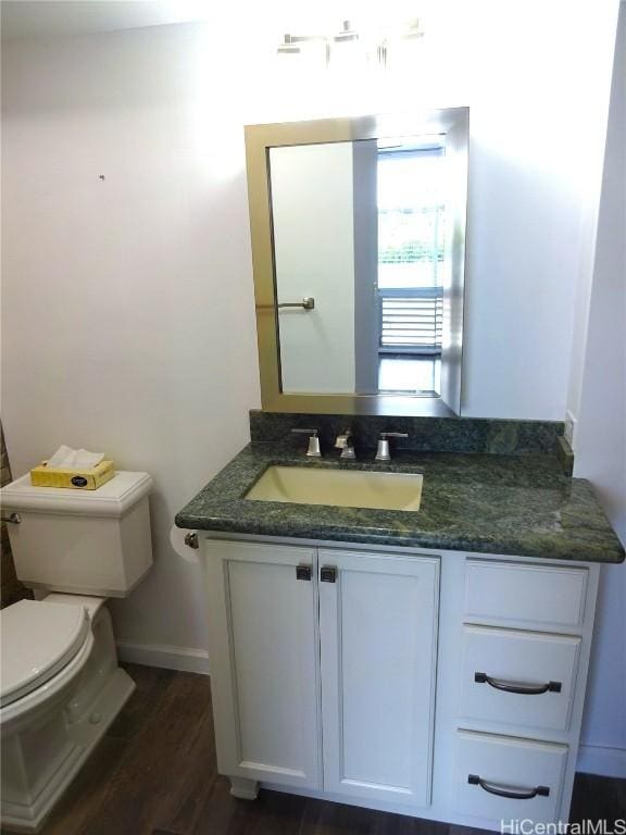 half bathroom featuring vanity, wood finished floors, and toilet