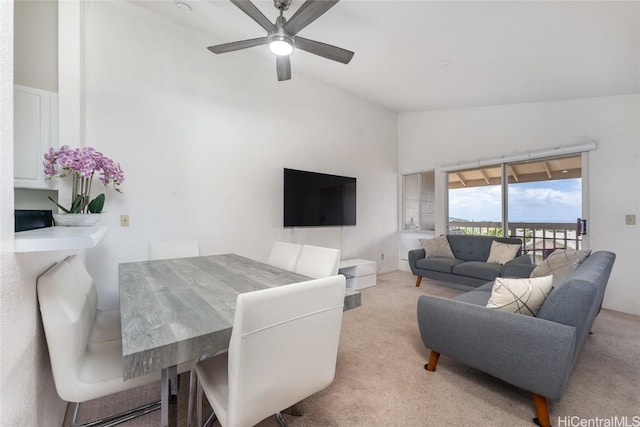 living area with a ceiling fan, vaulted ceiling, and light colored carpet