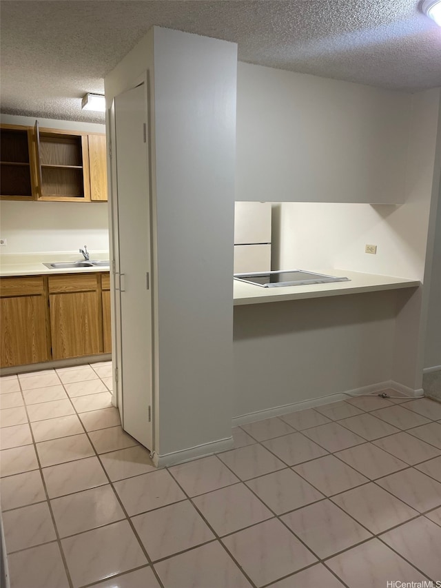 825 Coolidge St Unit 311, Honolulu, HI 96826 - kitchen with a textured ceiling, a sink, freestanding refrigerator, light tile patterned flooring, and light countertops