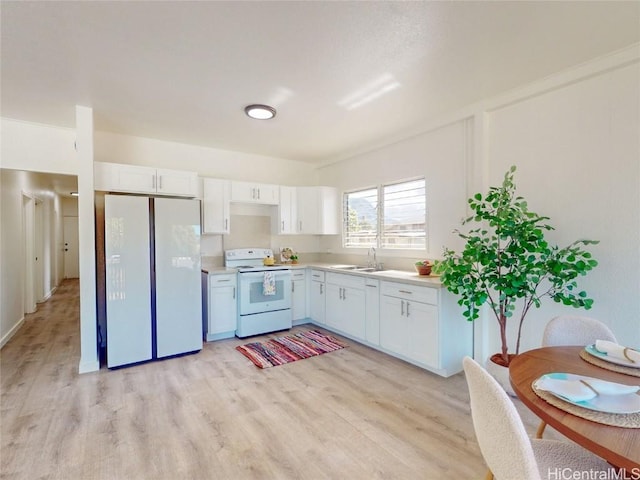 kitchen with white appliances, white cabinets, a sink, and light countertops