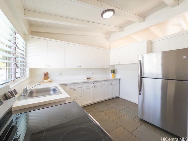 kitchen featuring lofted ceiling with beams, a sink, white cabinetry, light countertops, and freestanding refrigerator