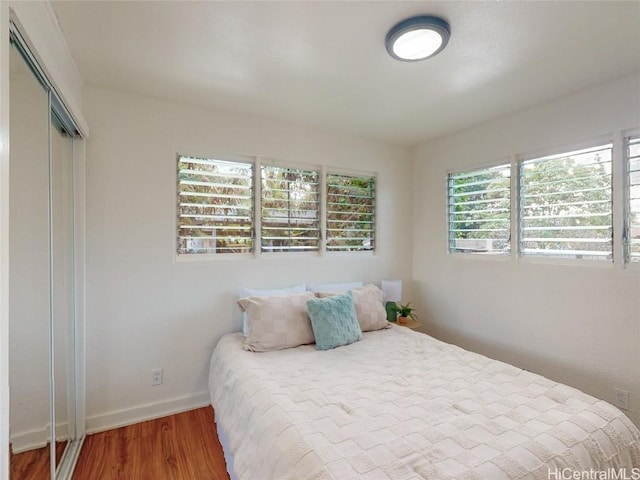 bedroom featuring a closet, wood finished floors, and baseboards