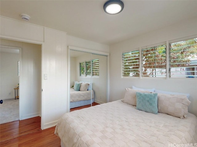 bedroom with a closet, wood finished floors, and baseboards