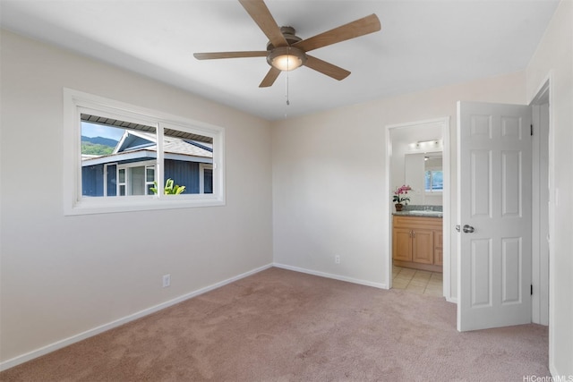 unfurnished bedroom with light carpet, connected bathroom, baseboards, and multiple windows