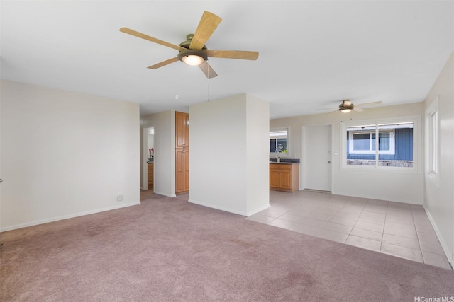 unfurnished room with ceiling fan, light colored carpet, baseboards, and light tile patterned floors