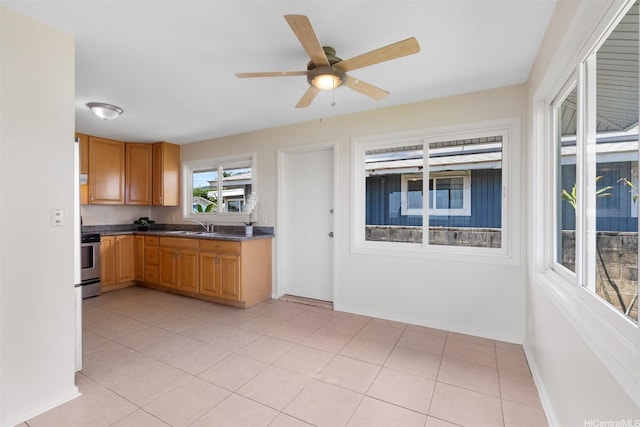kitchen with a ceiling fan, range, baseboards, a sink, and dark countertops