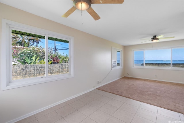 spare room with light tile patterned floors, light carpet, baseboards, and a ceiling fan