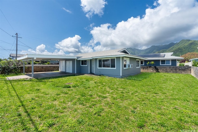 rear view of property featuring a yard, fence, a mountain view, and an attached carport