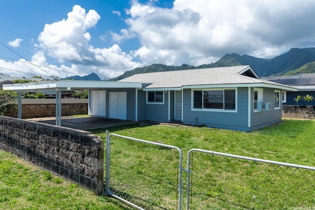 back of property with a yard, a mountain view, an attached garage, fence private yard, and a gate