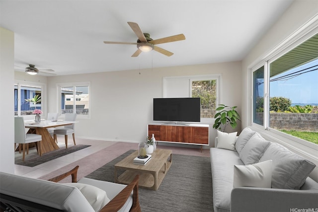 carpeted living area featuring plenty of natural light, baseboards, and ceiling fan
