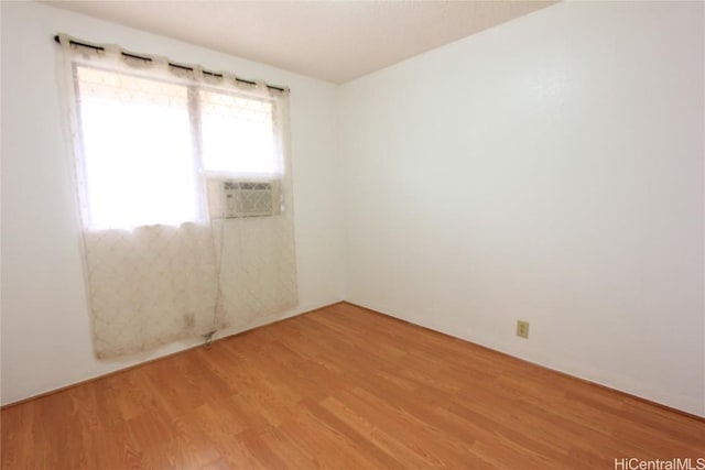 unfurnished room with cooling unit and light wood finished floors