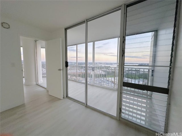 spare room with a wall of windows and wood finished floors