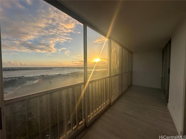 balcony at dusk featuring a water view