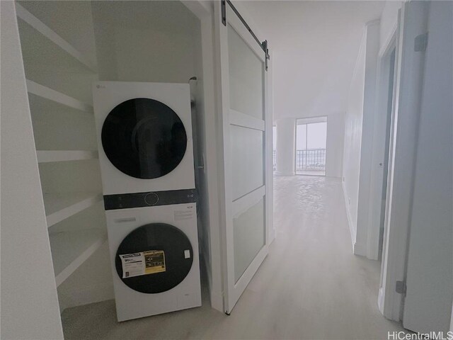 interior space featuring laundry area, a barn door, and stacked washer / drying machine