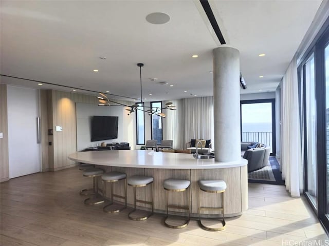 kitchen featuring ornate columns, light wood-type flooring, recessed lighting, light countertops, and open floor plan