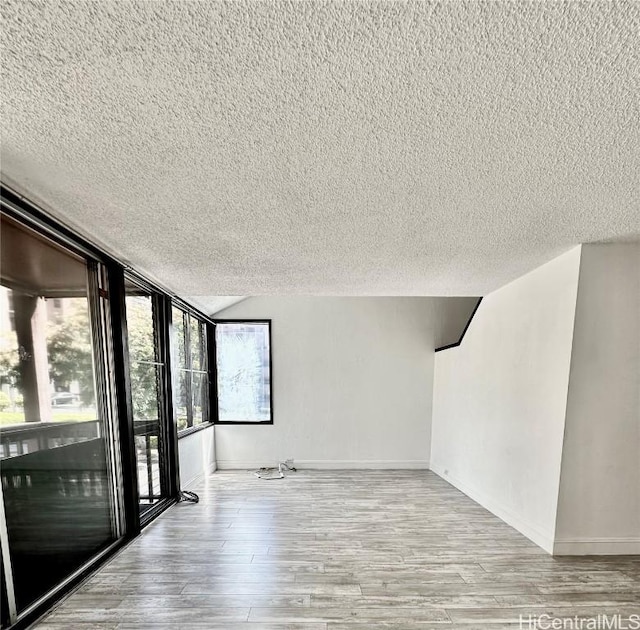 spare room featuring a textured ceiling, baseboards, and wood finished floors