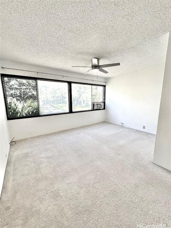 carpeted empty room with cooling unit, a textured ceiling, and a ceiling fan