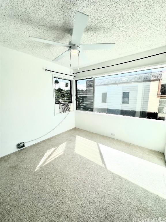 unfurnished room with ceiling fan, cooling unit, and a textured ceiling