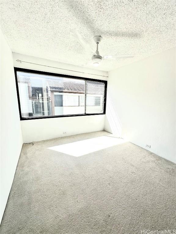 carpeted empty room with a textured ceiling and a ceiling fan