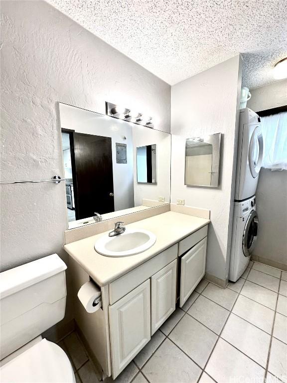 bathroom with a textured wall, toilet, a textured ceiling, and stacked washer / dryer