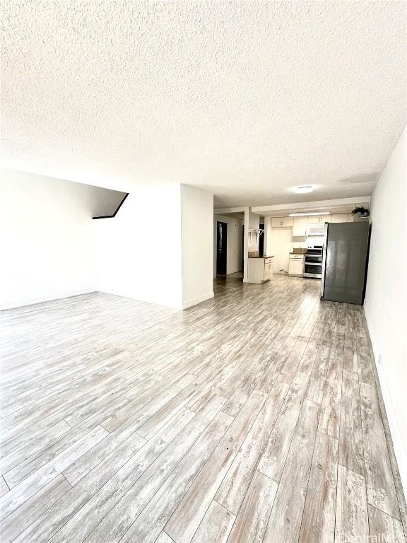 unfurnished living room with light wood-type flooring and a textured ceiling