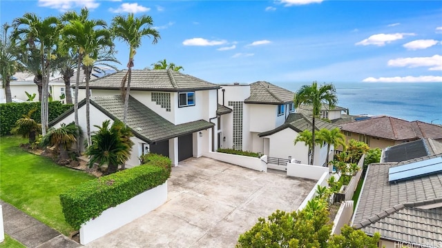 view of front facade with a water view, driveway, a tile roof, a residential view, and a front yard