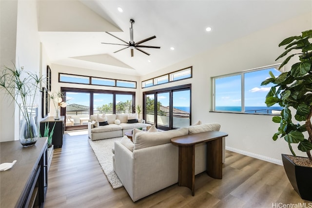 living room featuring a high ceiling, recessed lighting, wood finished floors, and baseboards