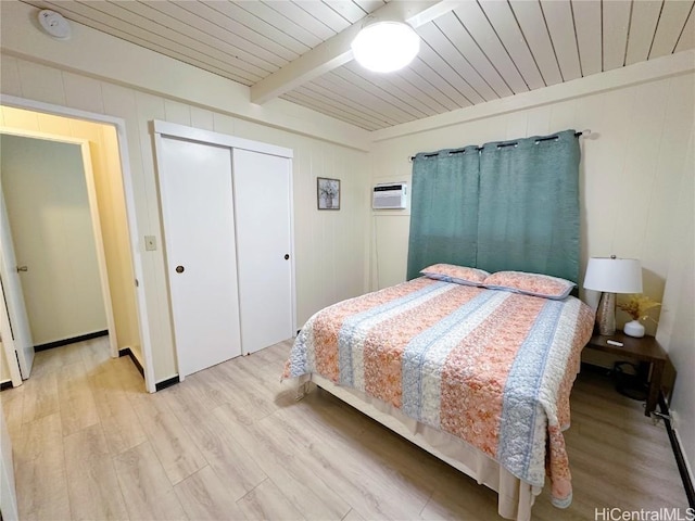 bedroom featuring wooden ceiling, wood finished floors, a wall mounted air conditioner, beam ceiling, and a closet