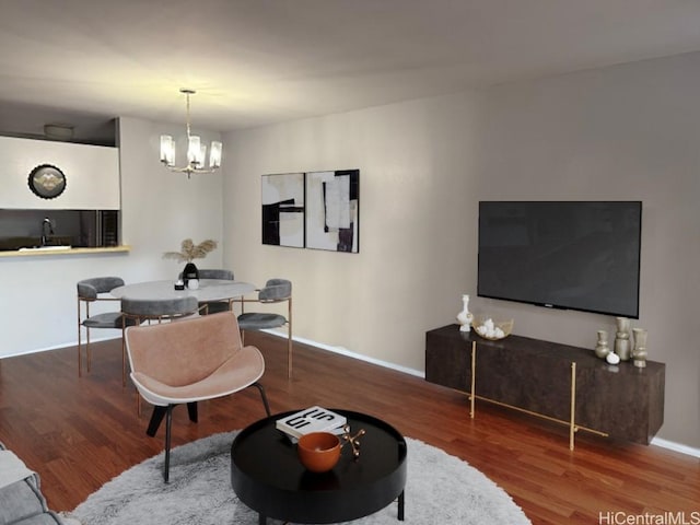 living room with baseboards, an inviting chandelier, and wood finished floors