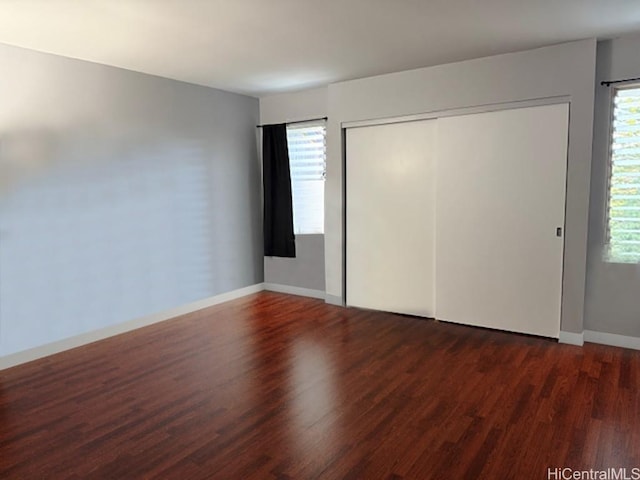 unfurnished bedroom with a closet, baseboards, and wood finished floors