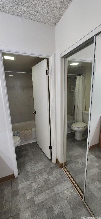 bathroom with baseboards, a textured ceiling, toilet, and shower / tub combo with curtain