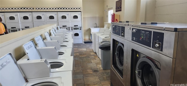 community laundry room with stone finish floor, stacked washing maching and dryer, and washing machine and clothes dryer