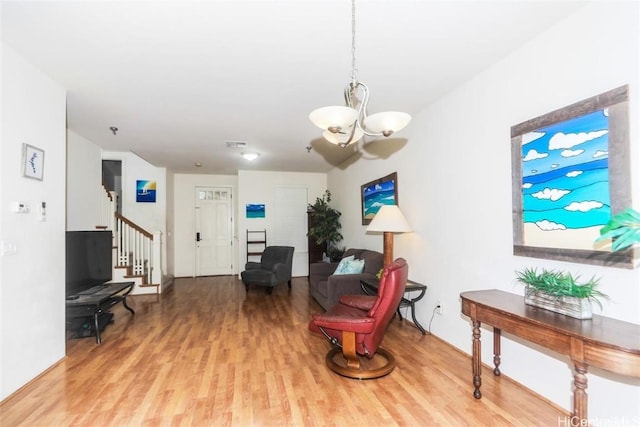 living area with stairway, an inviting chandelier, and wood finished floors