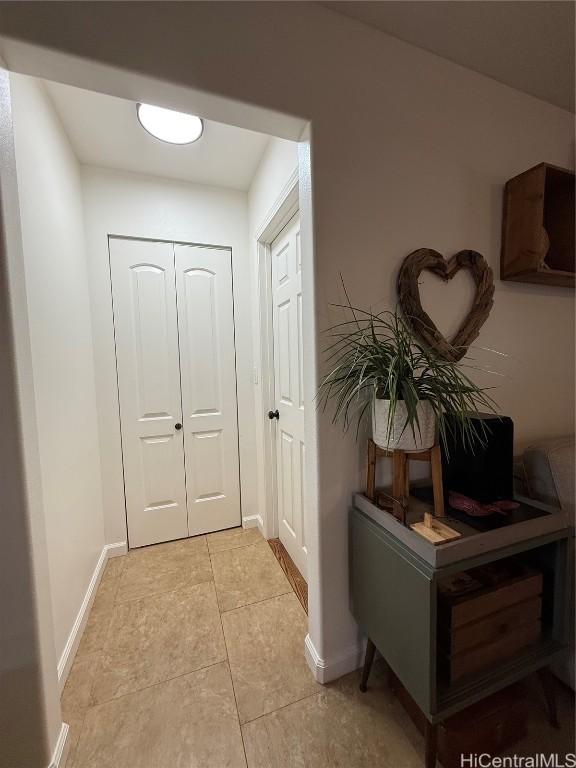 doorway with light tile patterned flooring and baseboards