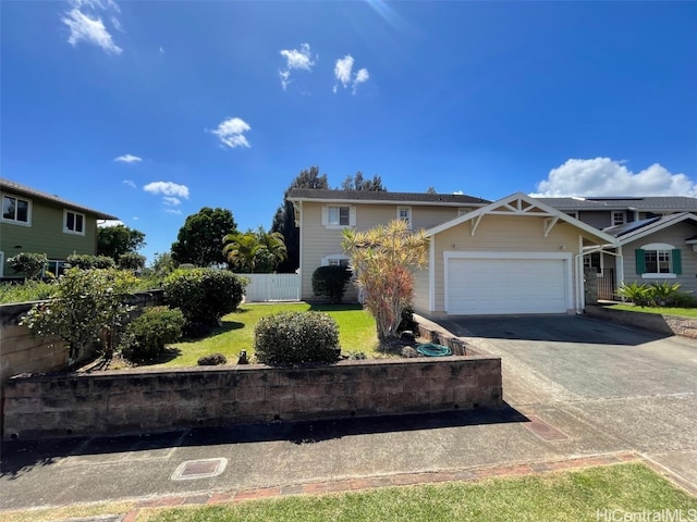 view of front of house with a garage, driveway, a front lawn, and fence