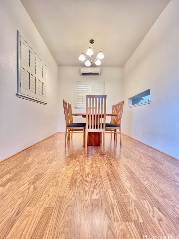 dining area with light wood-style floors, a wall mounted AC, and an inviting chandelier