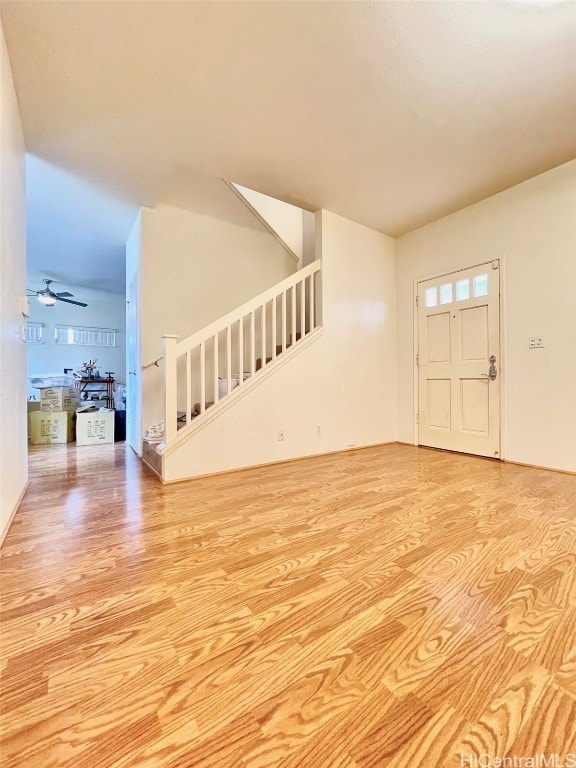 unfurnished living room with ceiling fan, stairs, and wood finished floors